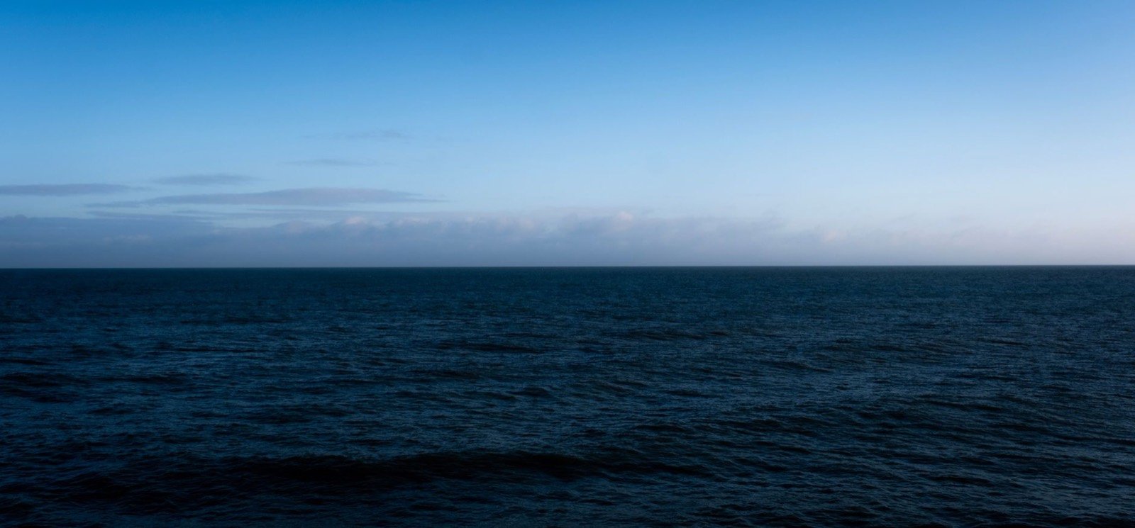 Mare calmo al crepuscolo, orizzonte blu petrolio
