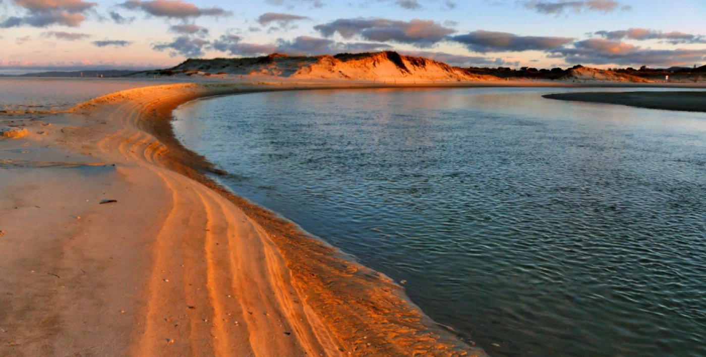 Riva di sabbia e acqua bassa al tramonto